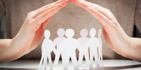 Zwei schützende Hände bilden ein Dach über einer Gruppe aus Papierfiguren – das Bild symbolisiert den Schutz der Betriebsräte. Zwei schützende Hände bilden ein Dach über einer Gruppe aus Papierfiguren – das Bild symbolisiert den Schutz der Betriebsräte.